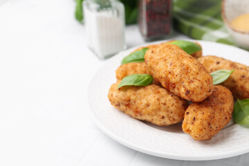 Tasty fried croquettes, basil and sauce on white tiled table, closeup. Space for text