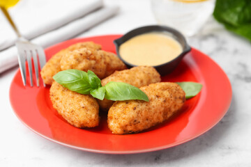 Tasty fried croquettes, basil and sauce on white marble table, closeup