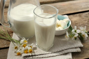 Fresh milk, mozzarella balls and flowers on wooden table, closeup. Dairy products