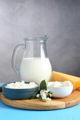 Different fresh dairy products and flowers on light blue wooden table, closeup