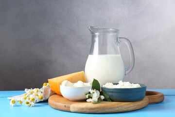 Different fresh dairy products and flowers on light blue wooden table
