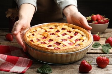 Woman with tasty strawberry pie at wooden table, closeup