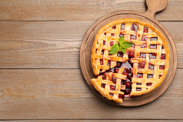 Tasty cut cherry pie on wooden table, top view. Space for text