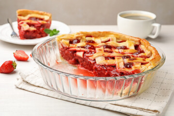 Tasty cut strawberry pie and berries on white wooden table, closeup