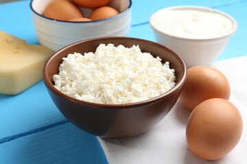 Different dairy products and eggs on light blue wooden table, closeup