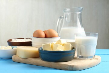 Different dairy products and eggs on light blue wooden table, closeup
