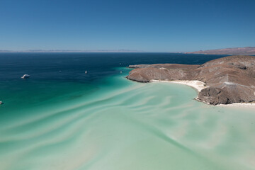 Stunning aerial view of Balandra Beach showcasing turquoise waters, white sandy shores, and rugged desert landscape under a clear blue sky