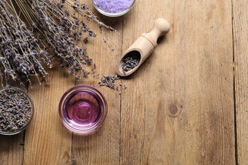 Natural essential oil and lavender flowers on wooden background, flat lay. Space for text