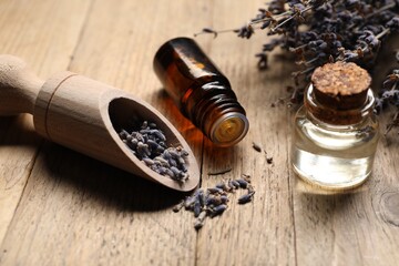 Natural essential oil and lavender flowers on wooden background, closeup