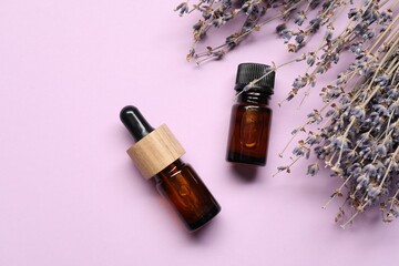 Natural essential oil and lavender flowers on lilac background, flat lay