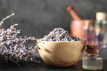 Natural essential oil and lavender flowers on black table, closeup