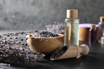 Natural essential oil and lavender flowers on black table, closeup