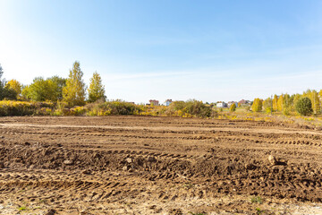 Empty land plot with tire prints prepared for new housing in rural area. Clearing and leveling of...