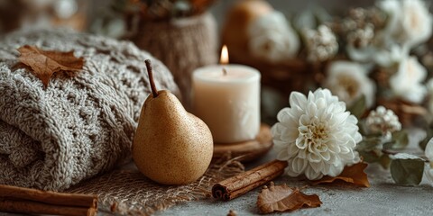 Cozy autumn-themed still life with bitten pear, candle, white flower, cinnamon, knitted blanket, and fall leaves evoking warmth and seasonal home decor