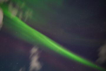 Stunning display of the aurora borealis with vibrant green lights streaking across a starry night sky, creating a mesmerizing natural spectacle