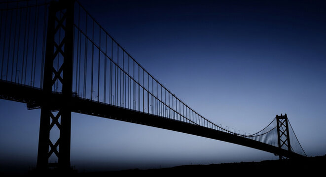 Majestic suspension bridge silhouetted against a twilight sky, showcasing its intricate steel structure and elegant design.