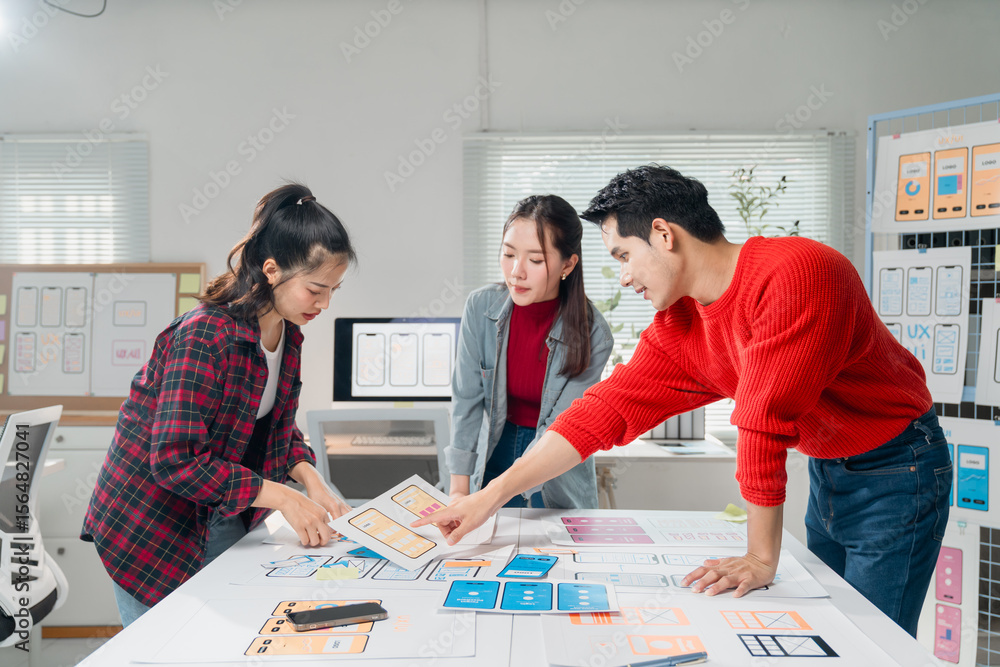 Poster creative team working together on mobile app design, analyzing wireframes and user interface layouts