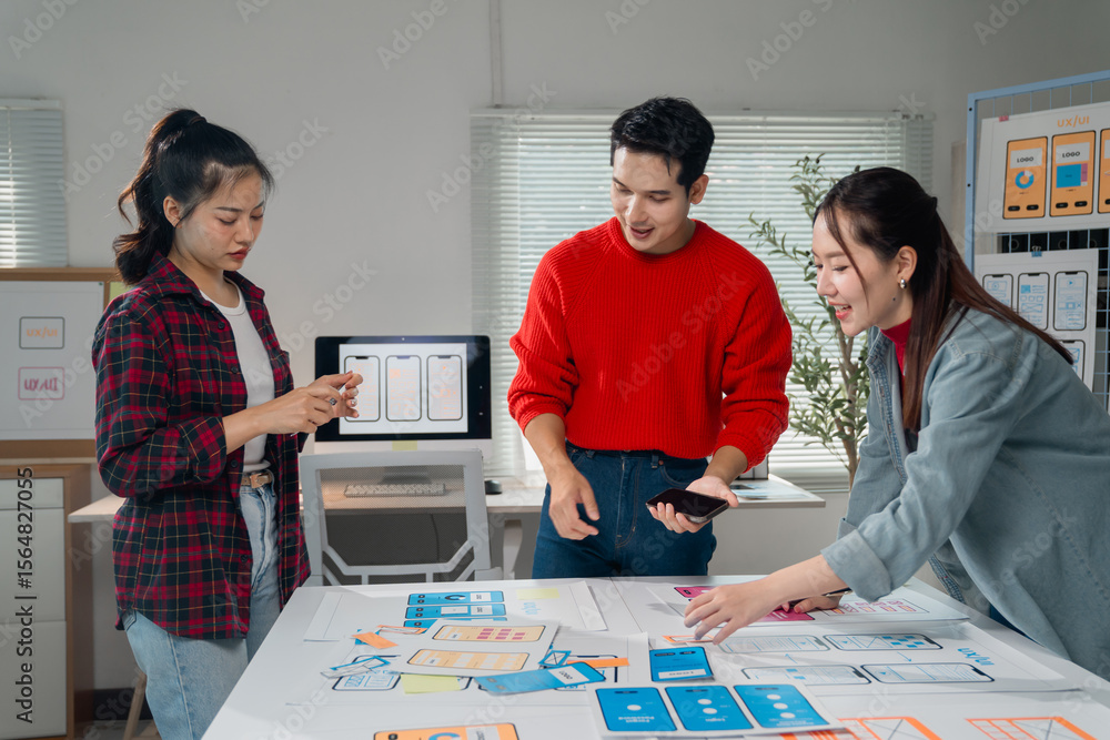 Poster three young asian ux ui designers are working together developing a mobile app design for their clie