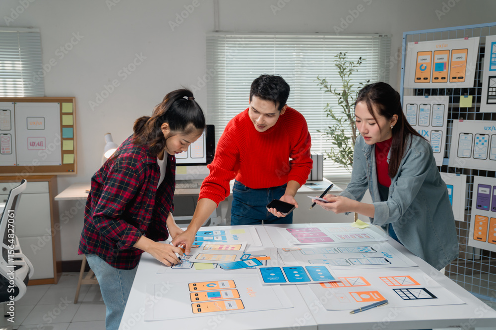 Poster asian ux designers collaborating in an office, creating and refining a user interface for a mobile a