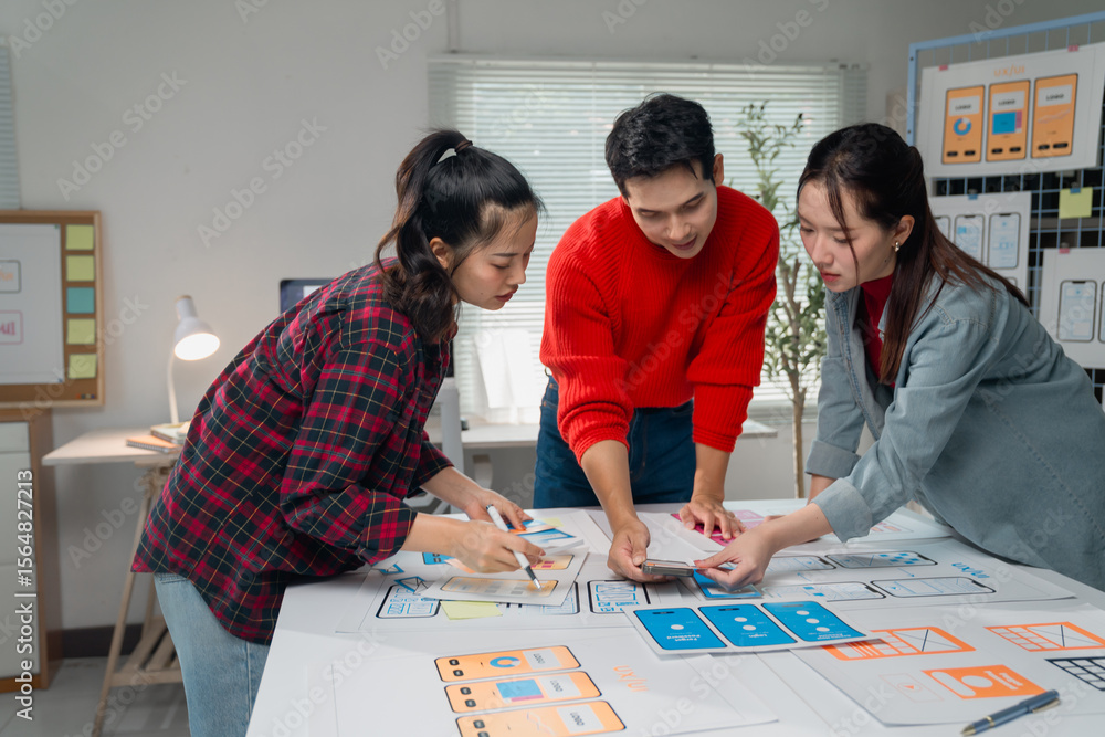 Poster asian ux designers team working together on mobile app interface wireframe design with a smartphone 