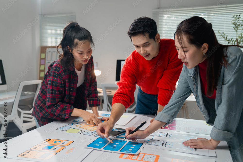 Poster three asian ux designers working together on a new mobile application prototype, discussing function