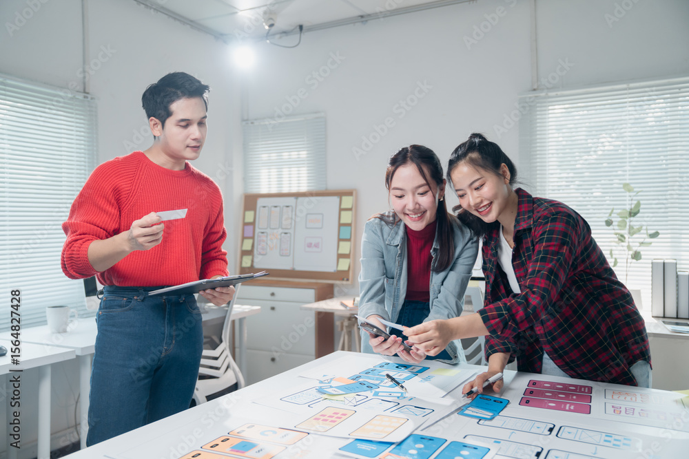 Poster young professionals engaged in a collaborative app design session. they are discussing layouts and f