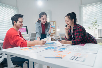 Diverse group of young professionals engaging in a collaborative design session. They are brainstorming and reviewing digital interface layouts in a modern, well-lit office space