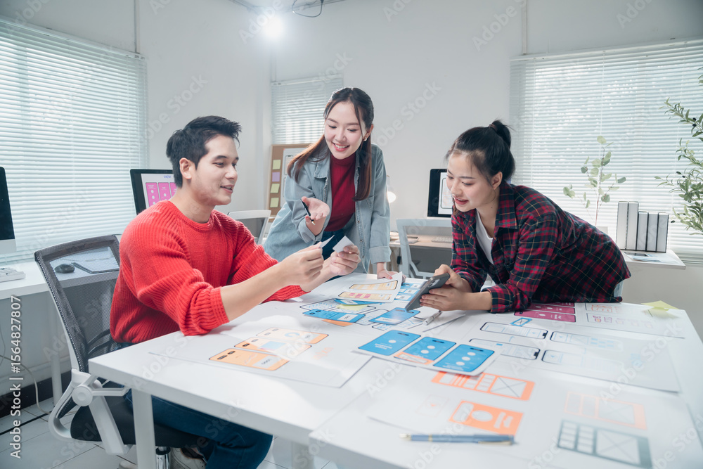 Poster three asian ux designers are working together on developing mobile app interface wireframe design in