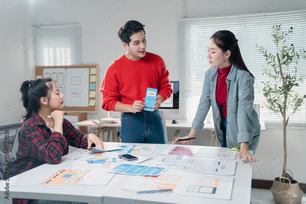 Poster young asian ux designers are discussing mobile app interface wireframes and layouts during a meeting