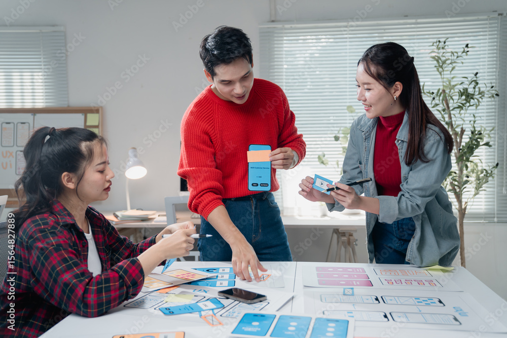  three asian ux designers working together on a new mobile application prototype, discussing the user