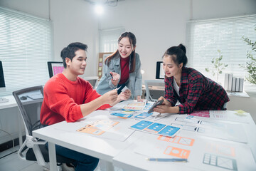 Three Asian ux designers are working together on developing mobile app interface wireframe design...