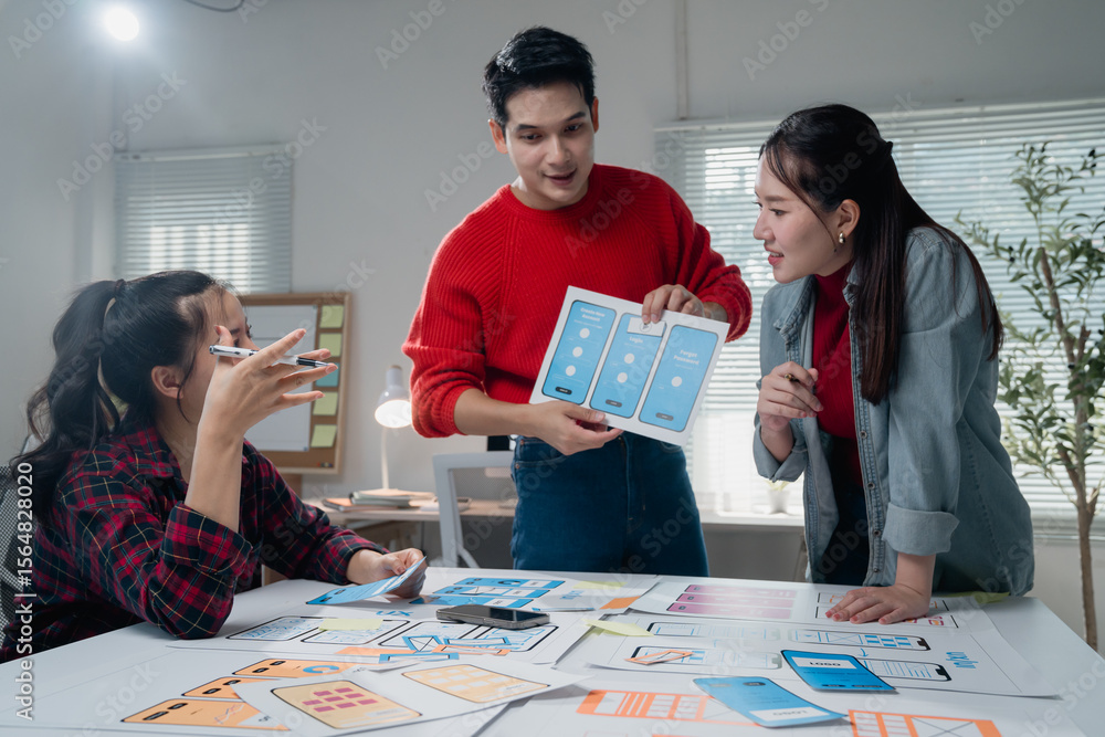 Poster diverse team of young designers engaged in a collaborative mobile app development meeting, analyzing