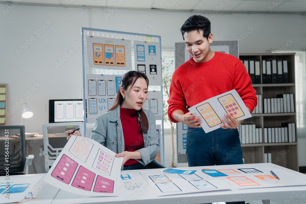 Poster two young ui/ux designers working together on new mobile app templates in a luminous office, compari