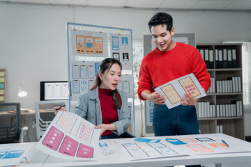 Two young ui/ux designers working together on new mobile app templates in a luminous office,...