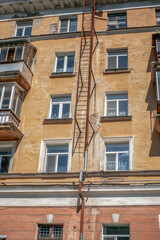 A fragment of an old fire escape on the facade of a house on a summer day