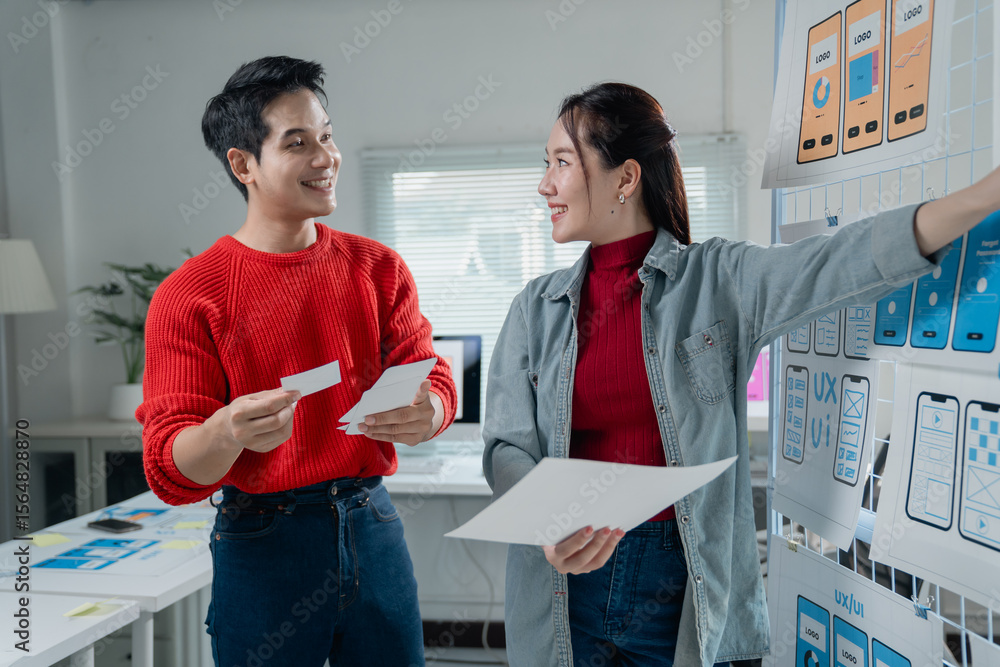 Poster two young asian colleagues reviewing user interface designs for mobile application development. coll