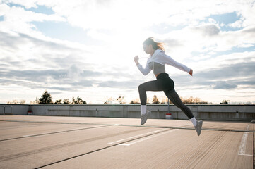 Woman Running on Rooftop Against Cloudy Sky