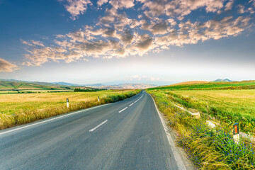 beautiful landscape of long road to amazing mountain scene from a green summer fields and hills....
