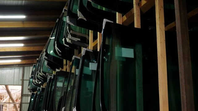 There are many different glasses for the car on the shelves of the car shop . New windshield and side windows on the shelves in the store. Salon for the replacement of car windows.