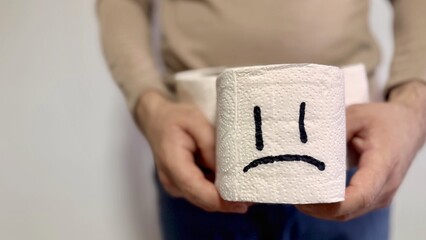 Digestive Problems and constipation. Man holding toilet paper with sad face. Toilet paper with sad face. 