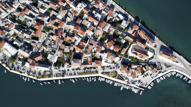 Aerial view of a peninsula with tightly packed buildings and boats dotting the coastline, a vibrant contrast against the deep blue sea, Vranjic, Split-Dalmatia County, Croatia.