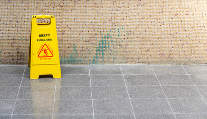 Warning sign indicating wet floor in a public area during daytime