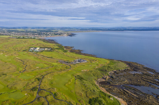 Aerial view of The Castle Course, where verdant fairways meet the rugged coastline under a vast sky, St Andrews, Scotland, United Kingdom.