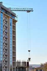 Workers use a crane to lift construction materials at a high-rise building site during bright...