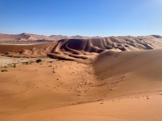 Aerial view of the iconic red sand dunes of Sossusvlei in Namibia’s Namib Desert under a clear...