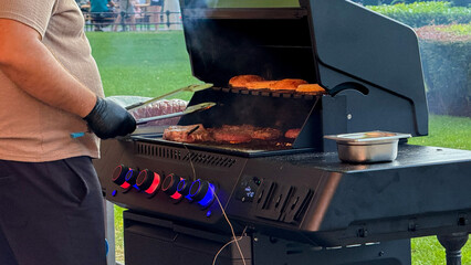 Festive barbecue symphony under azure skies, a Latino male adeptly grills, savoring flavors for...