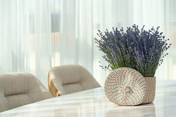 A woven basket filled with fresh lavender sits on a marble table, illuminated by natural light from...