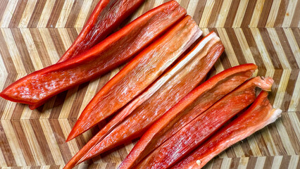 Carved crimson paprika slivers strewn like confetti on herringbone wood, celebrating Lunasa harvest...