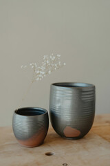 Two gray ceramic vases, one larger than the other, with subtle copper accents.
