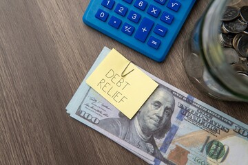 A stack of US hundred-dollar bills with a "DEBT RELIEF" note. Financial solutions, managing debt concept.